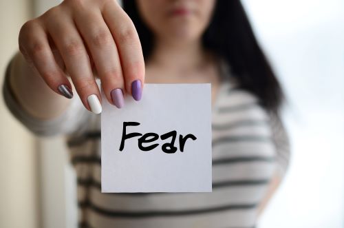 A girl holding a card written word Fear on it